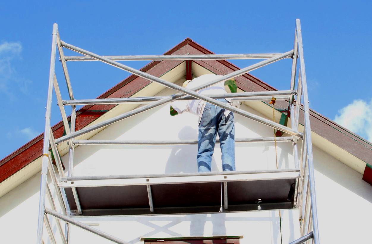 Photo of a person painting the trim of a house